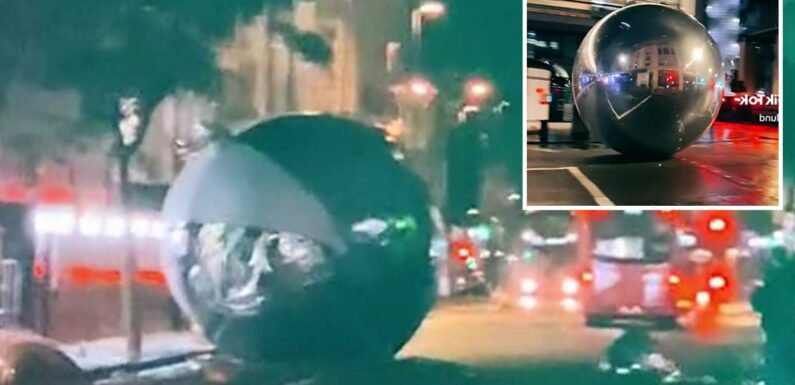 Moment giant Christmas baubles bigger than cars roll down London street after high winds blow them down | The Sun