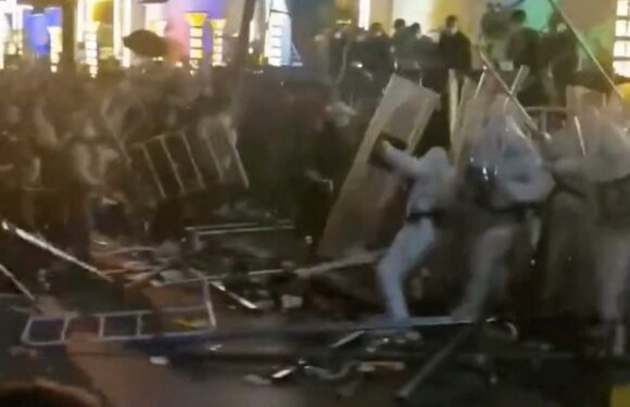 Moment workers at world's biggest iPhone factory attack cops in hazmat suits with metal railings as riots break out | The Sun