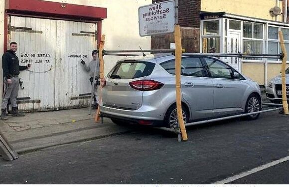 Businessman builds scaffolding to block car outside warehouse