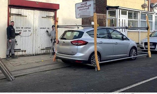Businessman builds scaffolding to block car outside warehouse