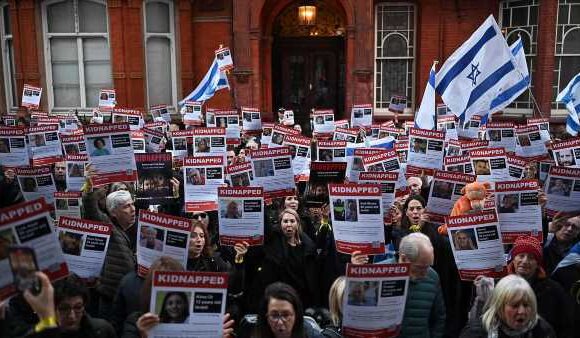 Protesters waving Israeli flags hold up posters of the missing