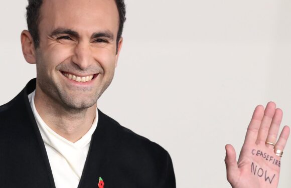 Khalid Abdalla writes Ceasefire NOW' on his hand at The Crown premiere